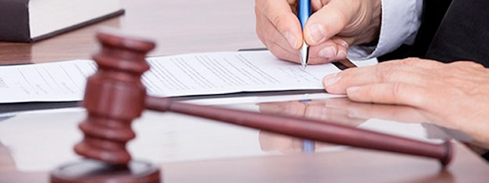 Judge signing papers with a gavel on his desk.