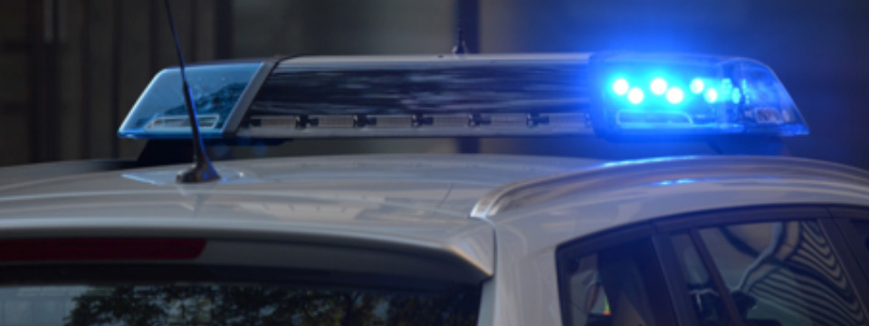 Close up of the top of a police car with the lights on.