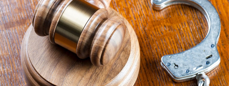 Judges gavel and pair of handcuffs sitting on the desk