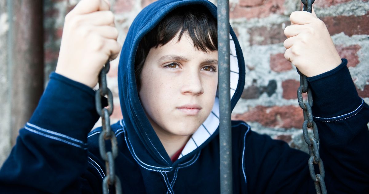 Boy behind bar holding chains