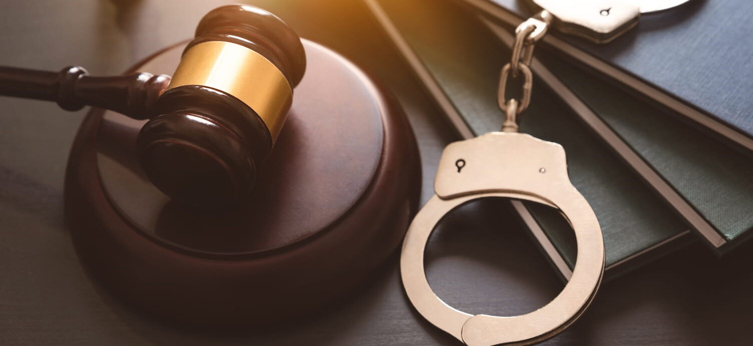 Handcuffs and wooden gavel on lawyer's desk