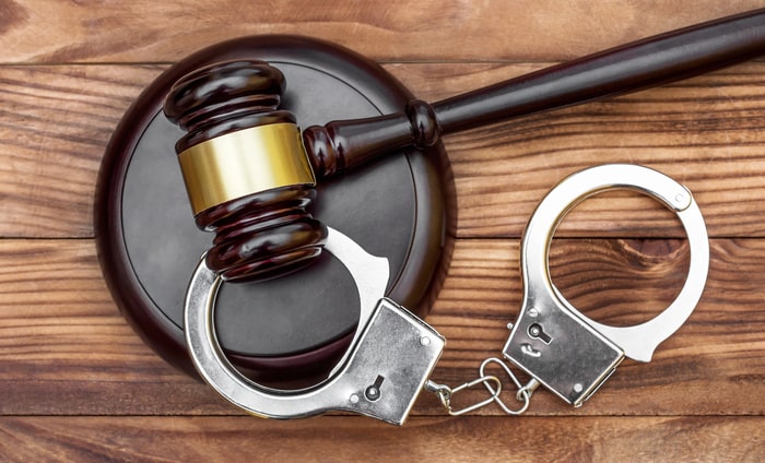 Gavel with stand and handcuffs on the wooden background.